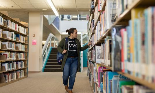 woman searching for a book on bookshelf